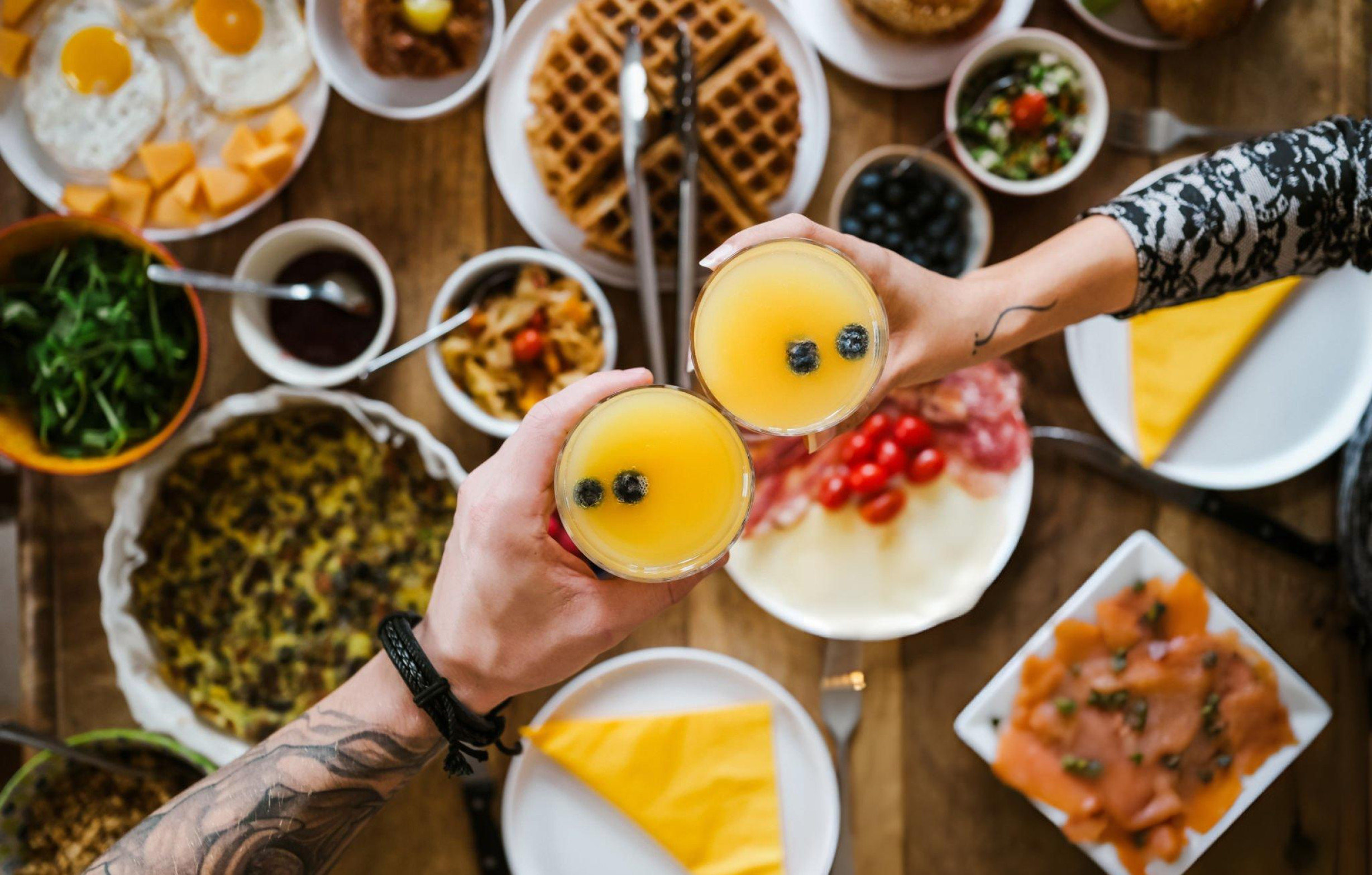 Brunch spread with waffles, eggs, orange juice and assorted dishes